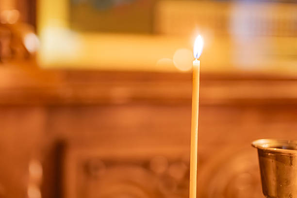 istock Image of a lit candle on an altar or table, emitting soft light in a religious context The image has a warm color palette dominated by orange and yellow tones, with a shallow depth of field to focus 2211184611