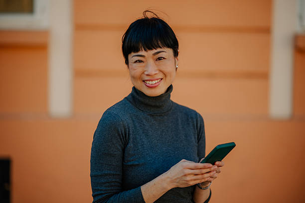 istock Smiling woman using smartphone in front of building 2211185648