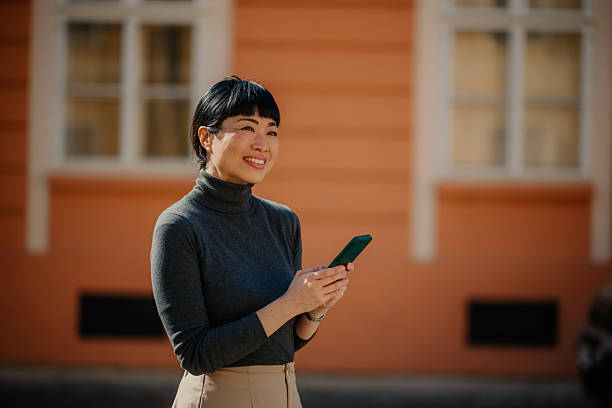 istock Smiling businesswoman using smartphone in urban setting 2211185651