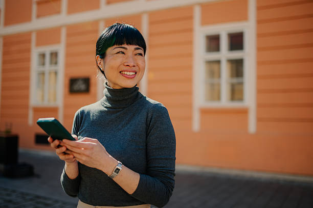 istock Smiling businesswoman using smartphone in front of building 2211185662
