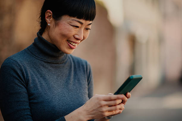 istock Smiling woman using smartphone on city street 2211185671