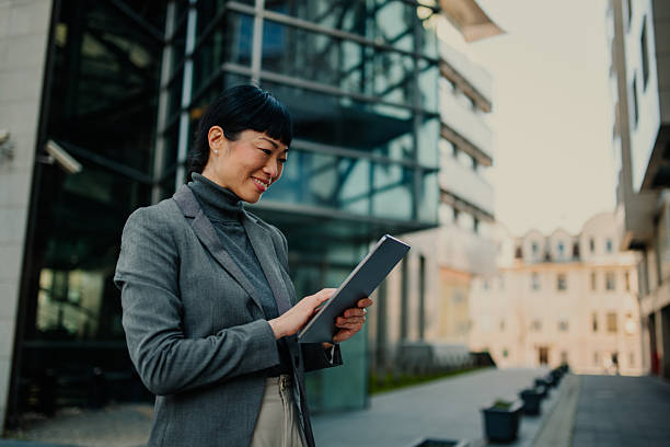 istock Smiling businesswoman using digital tablet in urban setting 2211185702