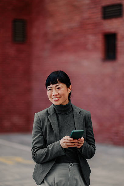 istock Smiling businesswoman using smartphone in urban setting 2211185736