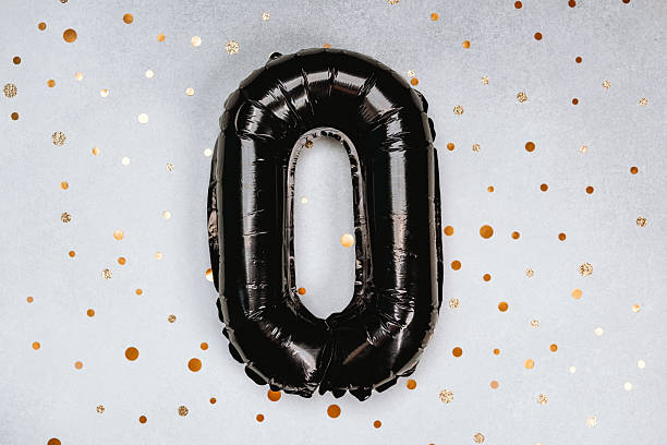 istock Black balloon shaped like a zero on a festive golden confetti background 2211186095