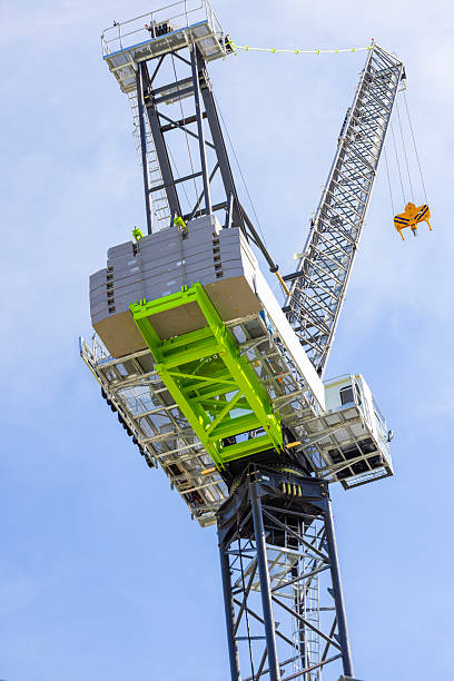 istock Closeup low angle view of modern tower crane against blue sky, background with copy space 2211187250