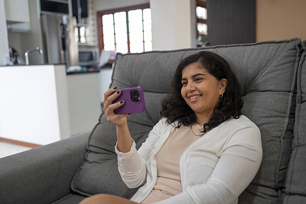 istock Latin woman using smartphone in living room at home 2211190854