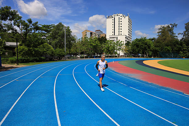 Senior Asian athlete is practicing running in the professional blue track for professional exercise, sport training workout and healthy for longevity