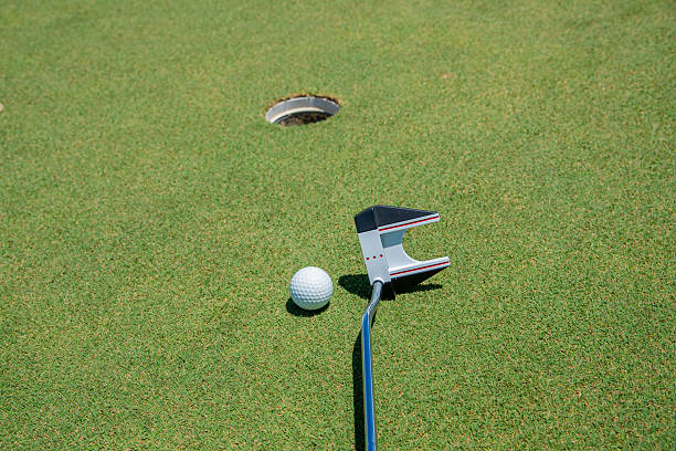 Clean, close-up photo of a golf ball resting in the hole on a manicured green, with the flagstick still in place. Ideal for golf success moments, sports achievements, putting precision, and golf course lifestyle imagery.