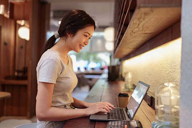 istock Young woman using laptop and browsing internet at modern cafe counter during casual solo work session 2211206167