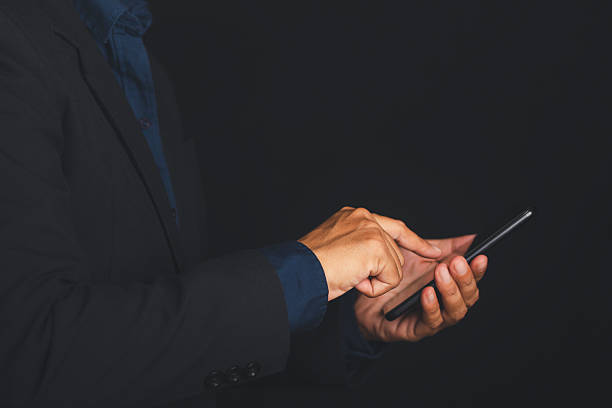 istock Businessman using smartphone in dark room, hands typing on screen. 2211209778