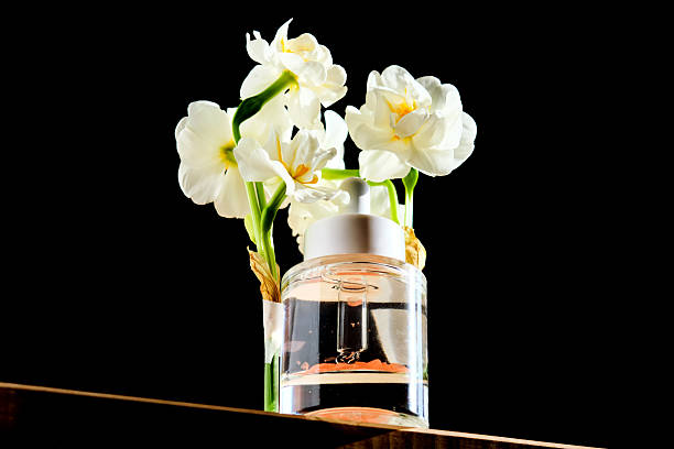 istock Serum bottle with petals on black background with daffodils. 2211210144