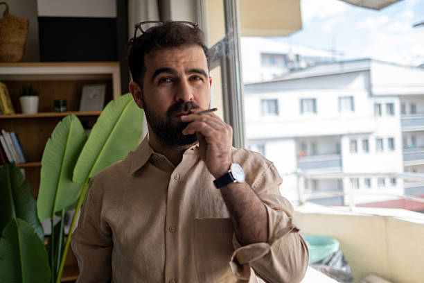 istock Young man smoking on the windowsill 2211212535