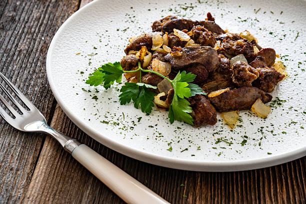 Fried chicken liver with apple and potatoes on black wooden table