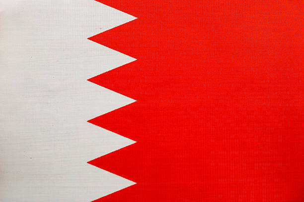 The Bahrain national flag features a red field with a white serrated band, prominently displayed against a bright blue background, symbolizing national pride.