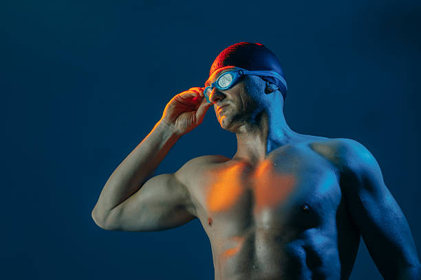 istock Focused swimmer in goggles and cap, lit by contrasting lights, ready to dive into action. 2211219276