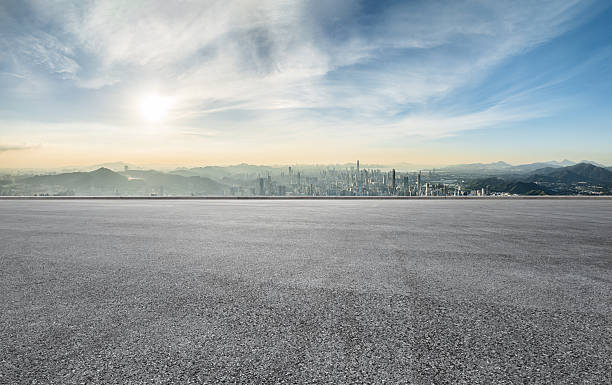 istock Empty asphalt road space and distant mountains with city skyline. 2211220494