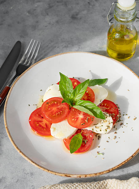 istock Caprese salad with sliced tomatoes, mozzarella and basil on a plate on a blue background 2211220965