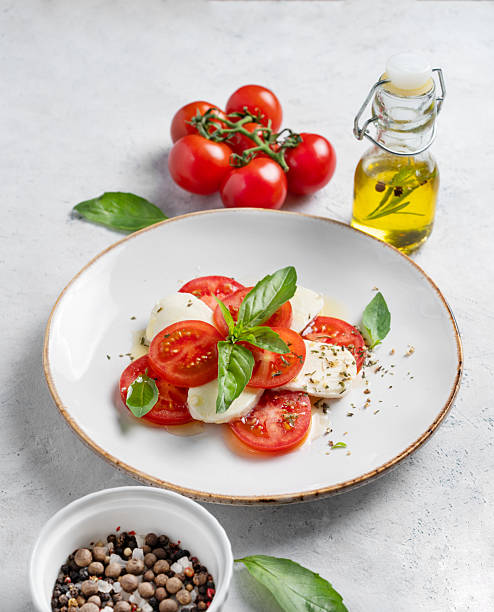 istock Caprese salad with sliced tomatoes, mozzarella and basil  on a light background 2211220966