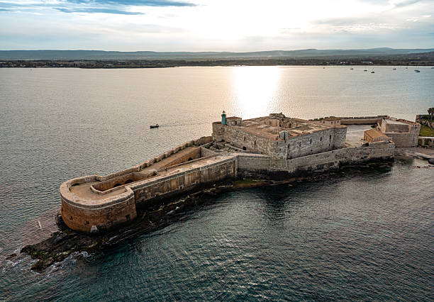istock Historic Coastal Fortification in Syracuse, Sicily Against a Tranquil Sea Sunset 2211222465