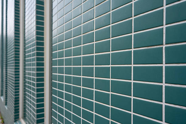 A close-up view of a green brick wall featuring white grout lines, showcasing geometric patterns and clean lines. The visual style is modern and minimalist, evoking a sense of order and precision. This image could be used for architectural design inspiration or as a background element in various creative projects.