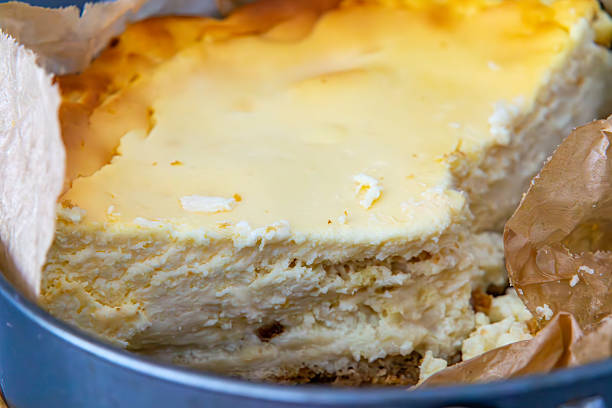 cheesecake – classic cheese cake with a light, creamy filling on a shortcrust pastry base, partially cut and placed in a cake tin lined with baking paper