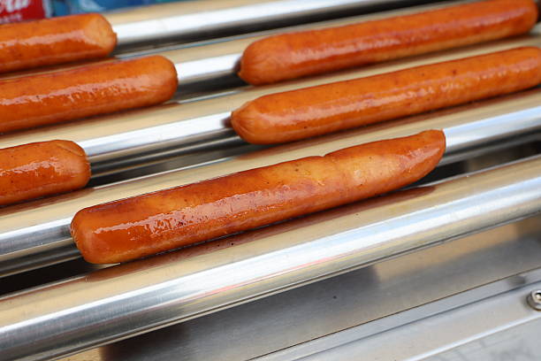 Sizzling Grilled Hot Dogs Being Cooked on a Roller Grill for Everyone to Enjoy Deliciously