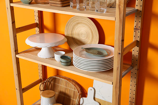 istock Wooden storage stand with kitchenware near orange wall indoors 2211225331