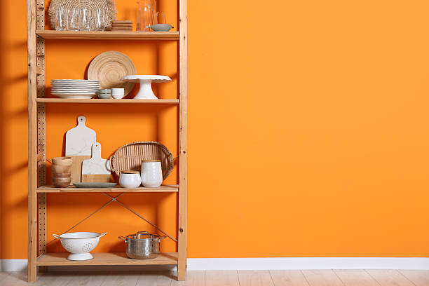 istock Wooden storage stand with kitchenware near orange wall indoors, space for text 2211225345