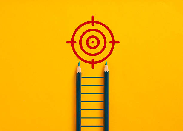 istock Pencils forming a ladder reaching a target on yellow background 2211227291