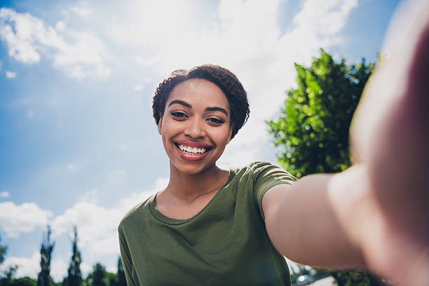 istock Charming young woman taking a selfie during a sunny day outdoors in a park 2211229015
