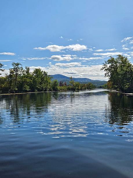 istock Serene river landscape with distant mountains and blue sky. 2211229558
