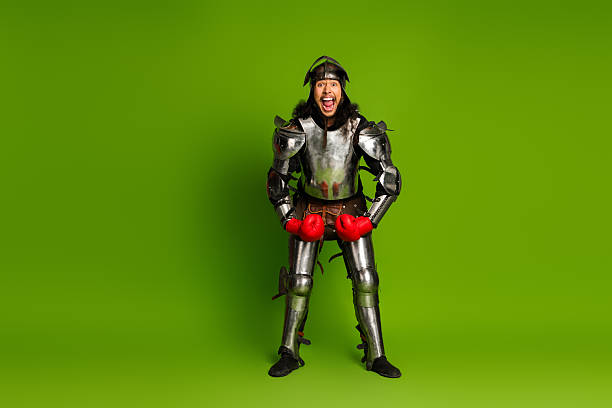 istock Knight in shining armor wearing red boxing gloves on green studio background 2211232682