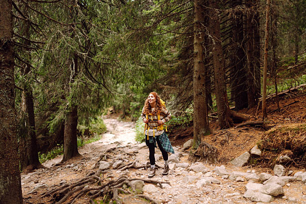 istock Young female hiker with hiking backpack walking up rocky path in lush green forest. 2211234614