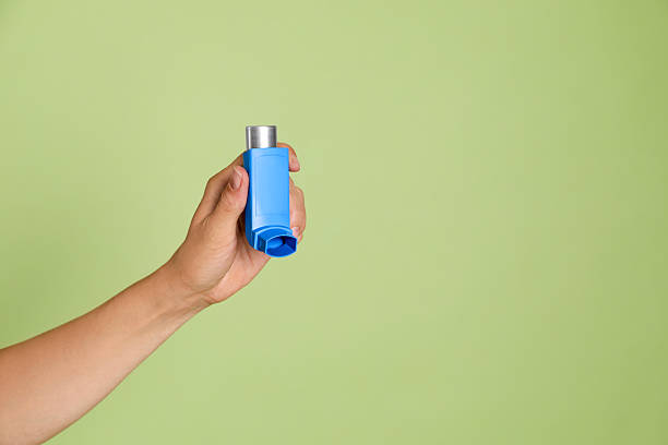 istock Woman holding asthma inhaler on olive background, closeup. Space for text 2211234687