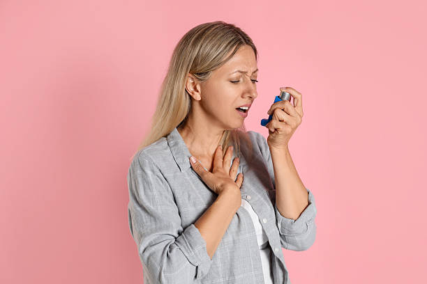 istock Woman using asthma inhaler on pink background 2211235030