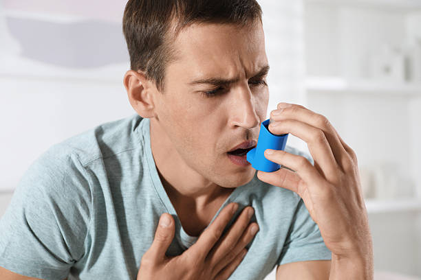 istock Man using inhaler at home. Asthma treatment 2211235119