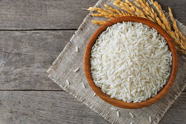 istock White rice filling wooden bowl on rustic table, complemented by delicate stalks 2211236742