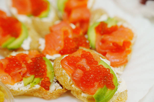 Sandwiches with avocado, red fish and caviar. A delicious gourmet snack with seafood.