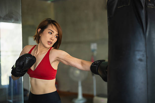 istock Young woman practicing boxing technique with a punching bag in a modern gym setting 2211238363