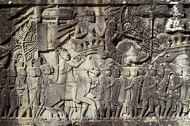 A breathtaking view of intricately carved stone faces adorning Angkor Thom Temple, located in Cambodia. The historic archaeological masterpiece highlights the skillful stonework and spiritual significance of ancient architecture and art.