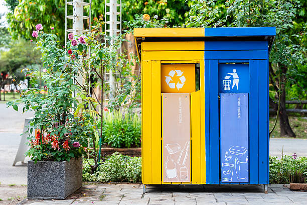 istock Garbage bins for sorting waste materials beside the walk way. Recycling bin stands at park. 2211240910