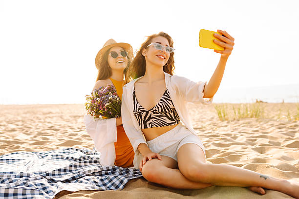 istock Two young women having fun on the beach and taking a selfie at sunset. 2211241849