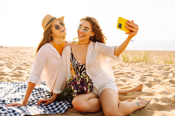 istock Two young women having fun on the beach and taking a selfie at sunset. 2211241855