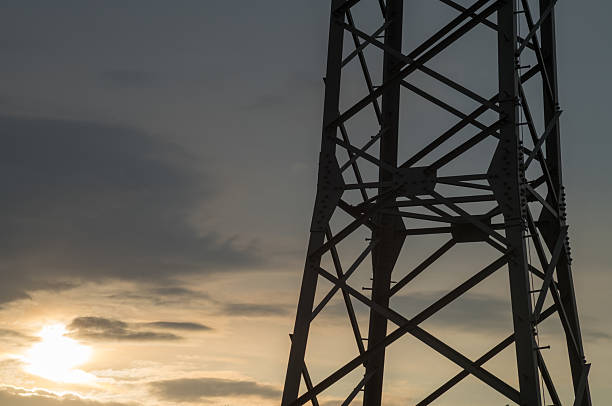 Metal electricity pylon standing tall against a beautiful cloudy sunset sky