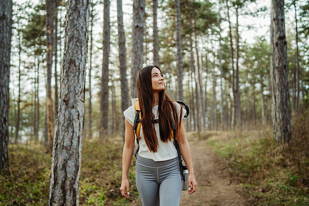 istock Young woman hike or trek and explore scenic forest with hiking sticks 2211248080