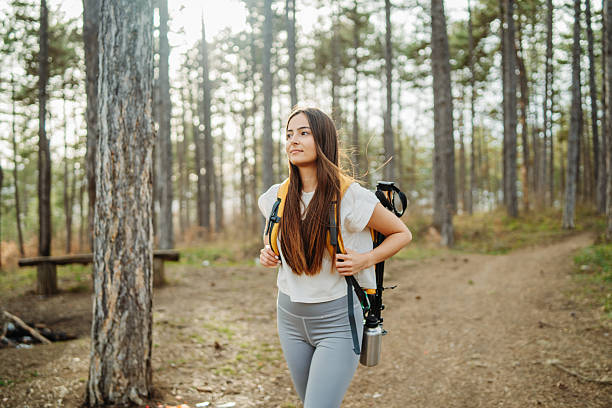istock Young woman hike or trek and explore scenic forest with hiking sticks 2211248081