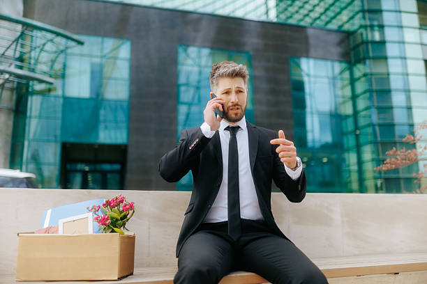 istock Man in suit faces job loss and despair while talking on phone outside office 2211250581