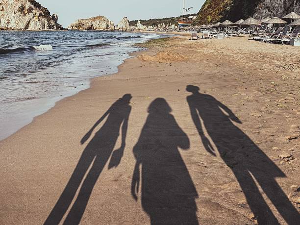 istock Shadows of Three People Walking Along a Peaceful Sandy Beach 2211255276