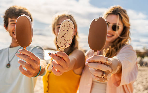 istock Young friends showing ice cream on a sunny beach 2211255506