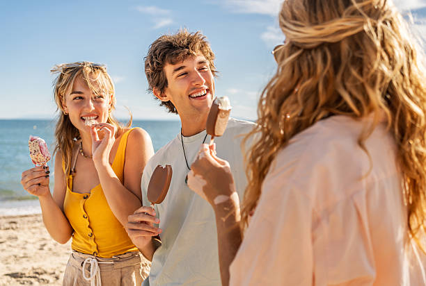 istock Young friends enjoying ice cream on sunny beach 2211255516